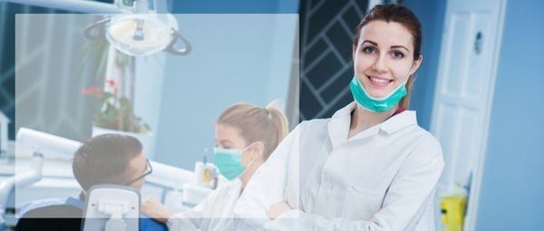 dentist in forefront while hygienist works with patient in background 101843908