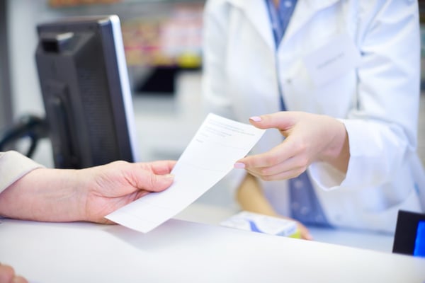 patient hands paper prescription to pharmacist 143926500
