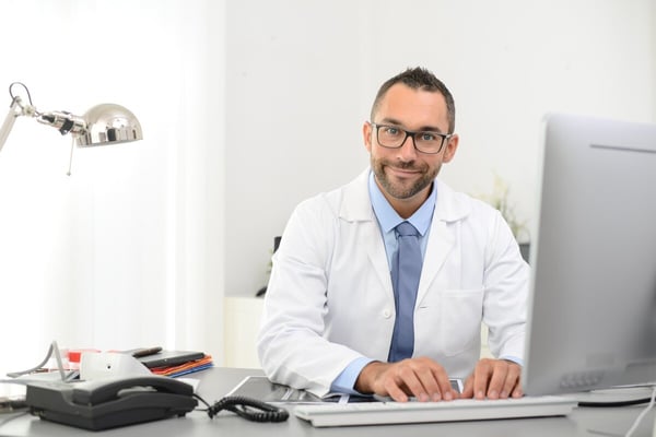 Male Healthcare Provider in lab coat works at desk 284817361