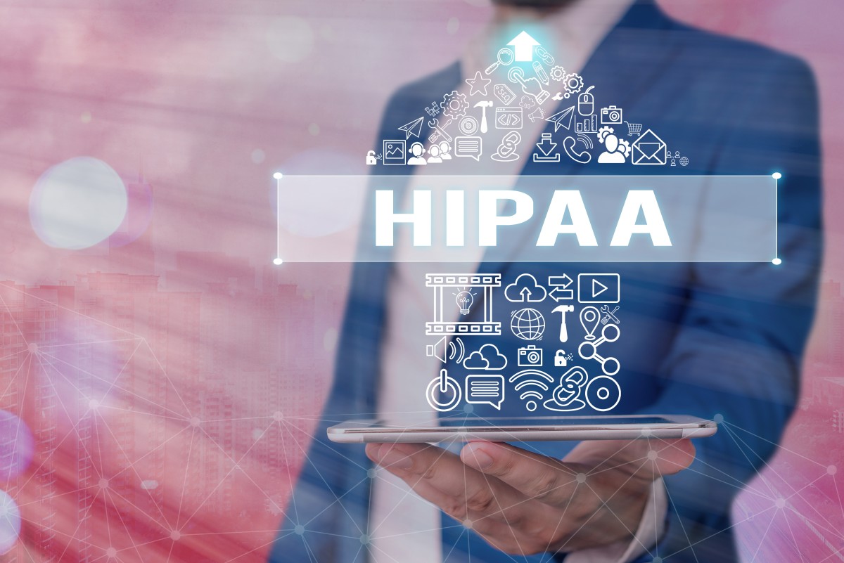 man holds open laptop with HIPAA and icons of HIPAA compliance 342616265