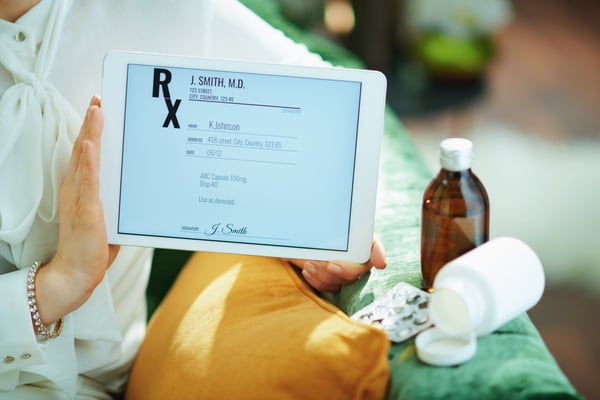 Tablet screen displays e prescription with prescription bottles in background 346190035