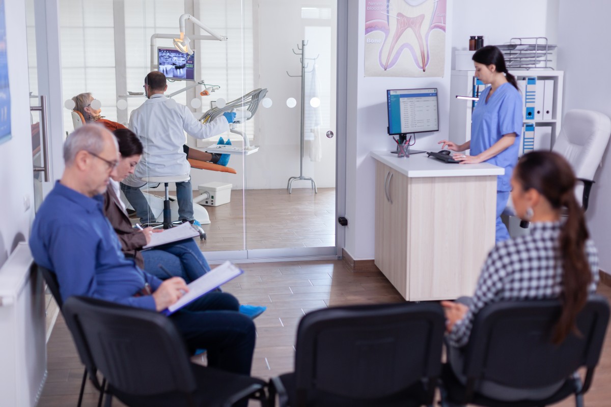 Dental tech validates insurance while dentist examines woman 427383000