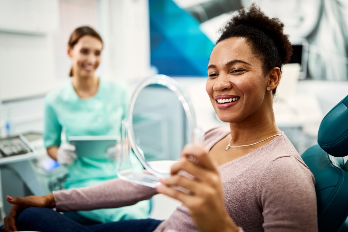 Female patient smiles in mirror as dentist looks on 458604959