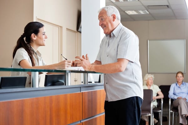 older gentleman talks to healthcare receptionist 48372571
