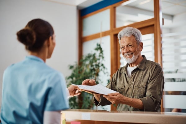 Smiling patient and administrative staff review paperwork 529396633