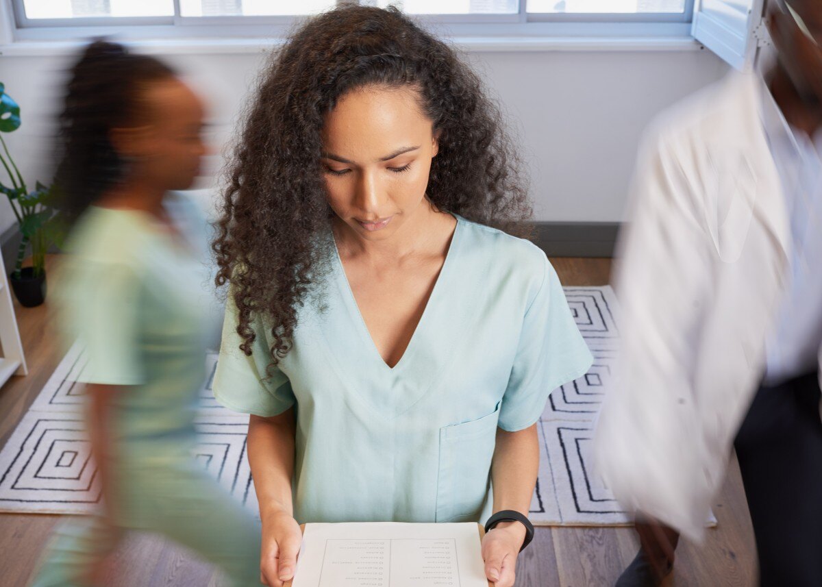 healthcare team member reviews paper work while others walk in background 584247897