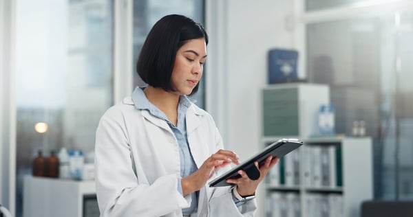 Healthcare provider uses tablet computer while standing in office 631222066