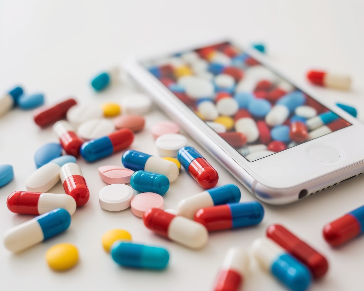 multi-colored pills spread out and image of those same pills on a phone screen 738111261