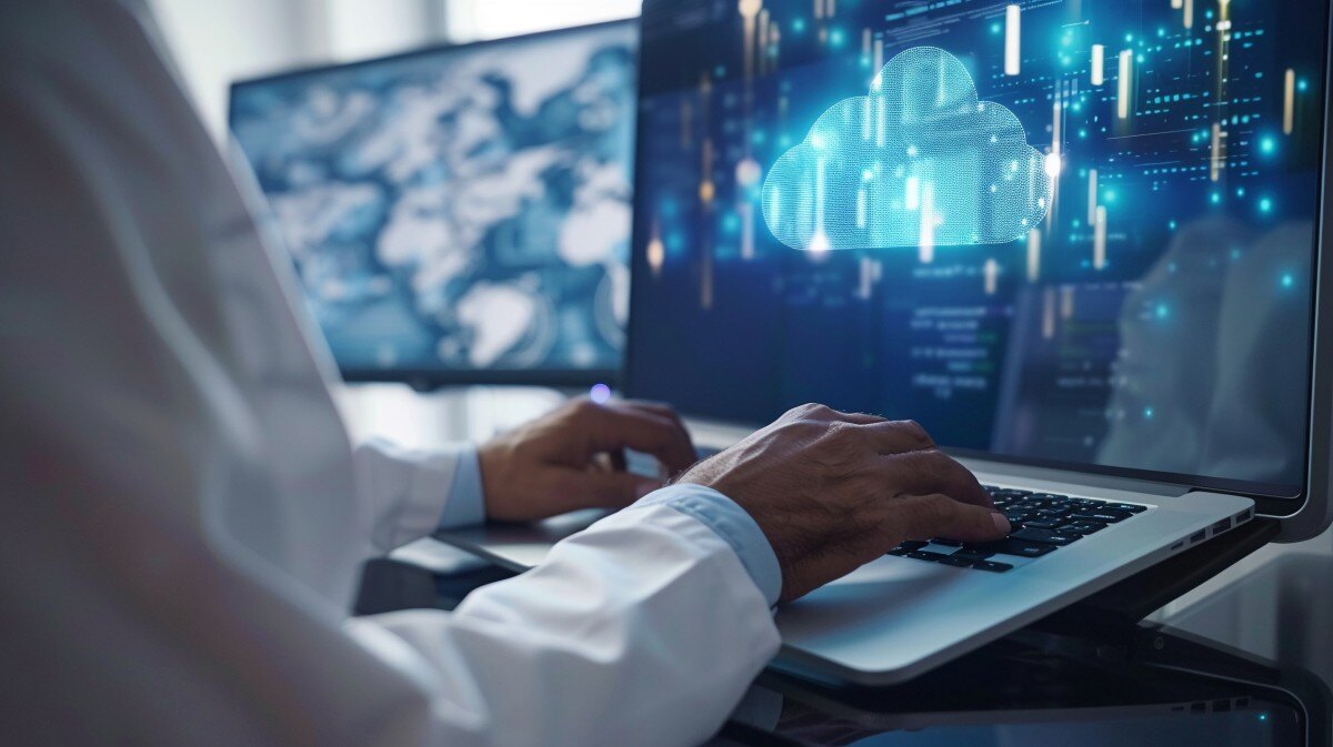 Person in lab coat at laptop with image of cloud and data on screen 824950372